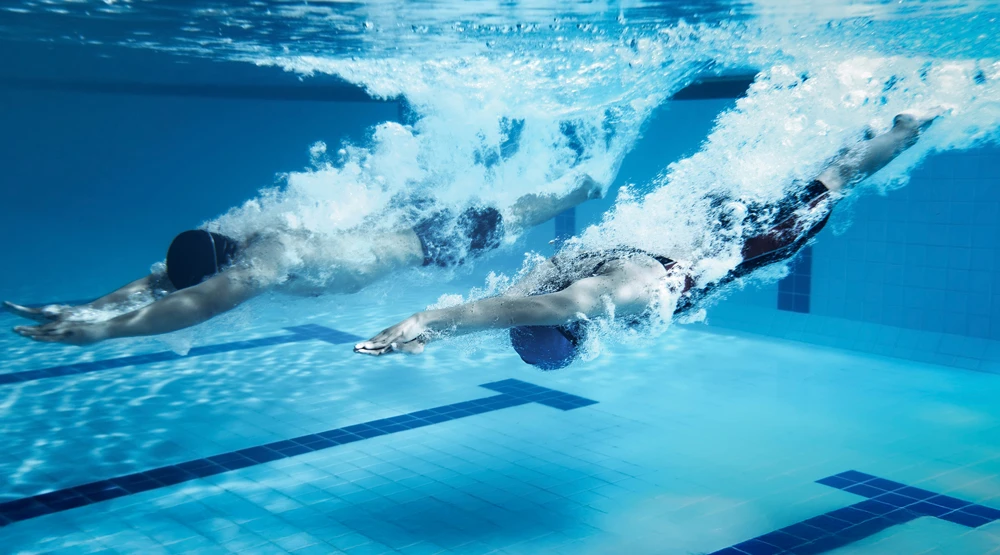 An underwater shot of a man and a woman right after diving into a pool