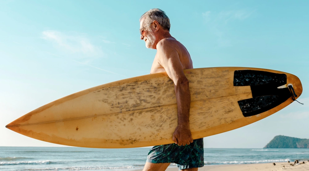 A man holding a surfboard walking toward the ocean