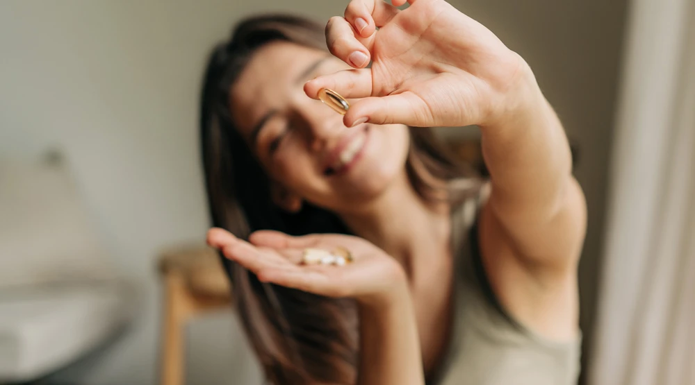 A smiling woman holding a small capsule