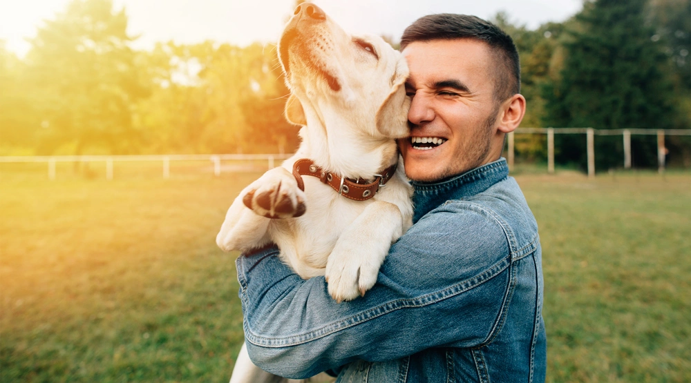 A man smiling while holding a dog in his arms