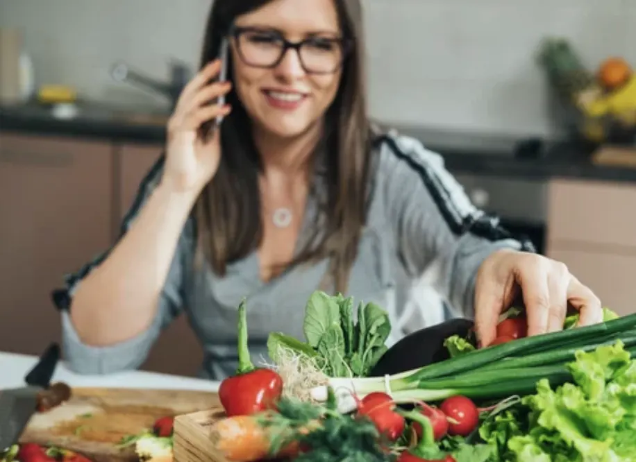 Homan talking on the phone while handling vegetables.